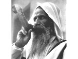 A Yemenite Jew of Jerusalem, draped in the `talith` (the customary prayer-shawl), announces the approach of the Sabbath on Friday by blowing a very long and curved ram`s-horn called a shophar. An early photograph.